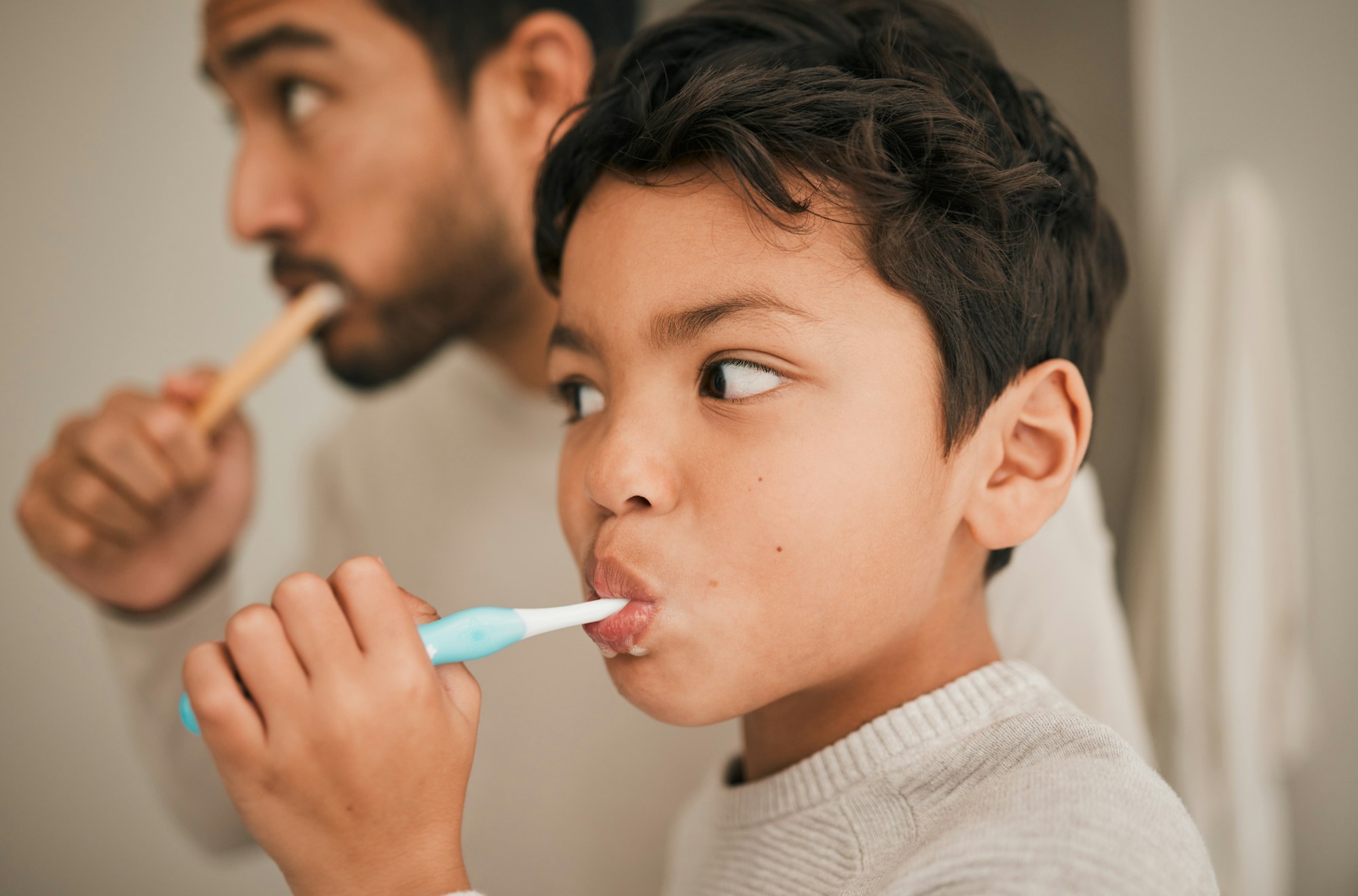 Father and young son brushing their teeth together, promoting good oral hygiene habits. Salthouse Smiles Pediatric Dentistry, Des Peres, MO, fostering children's dental health in the St. Louis area.