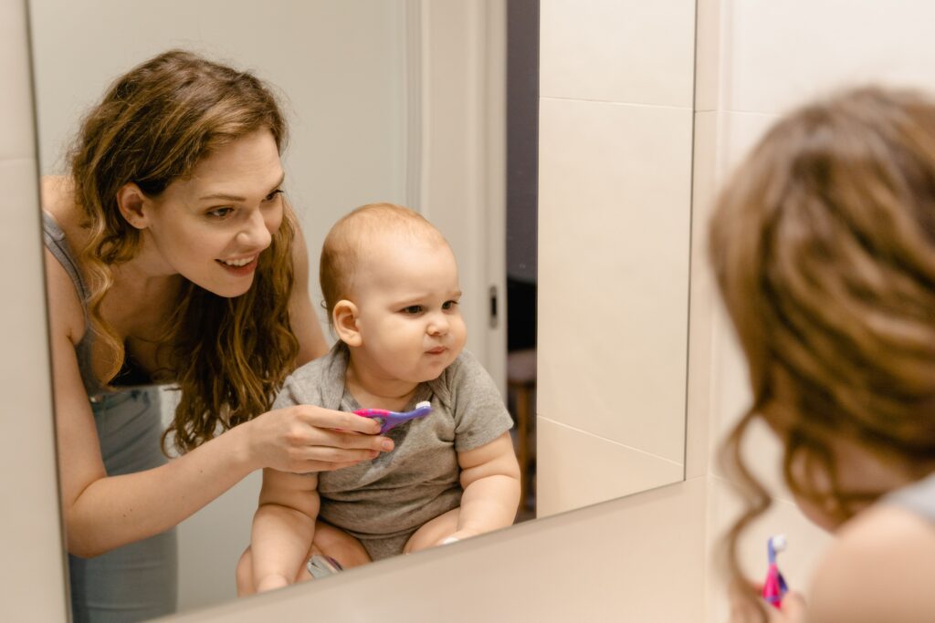 Parent helping a child brush their teeth at home.